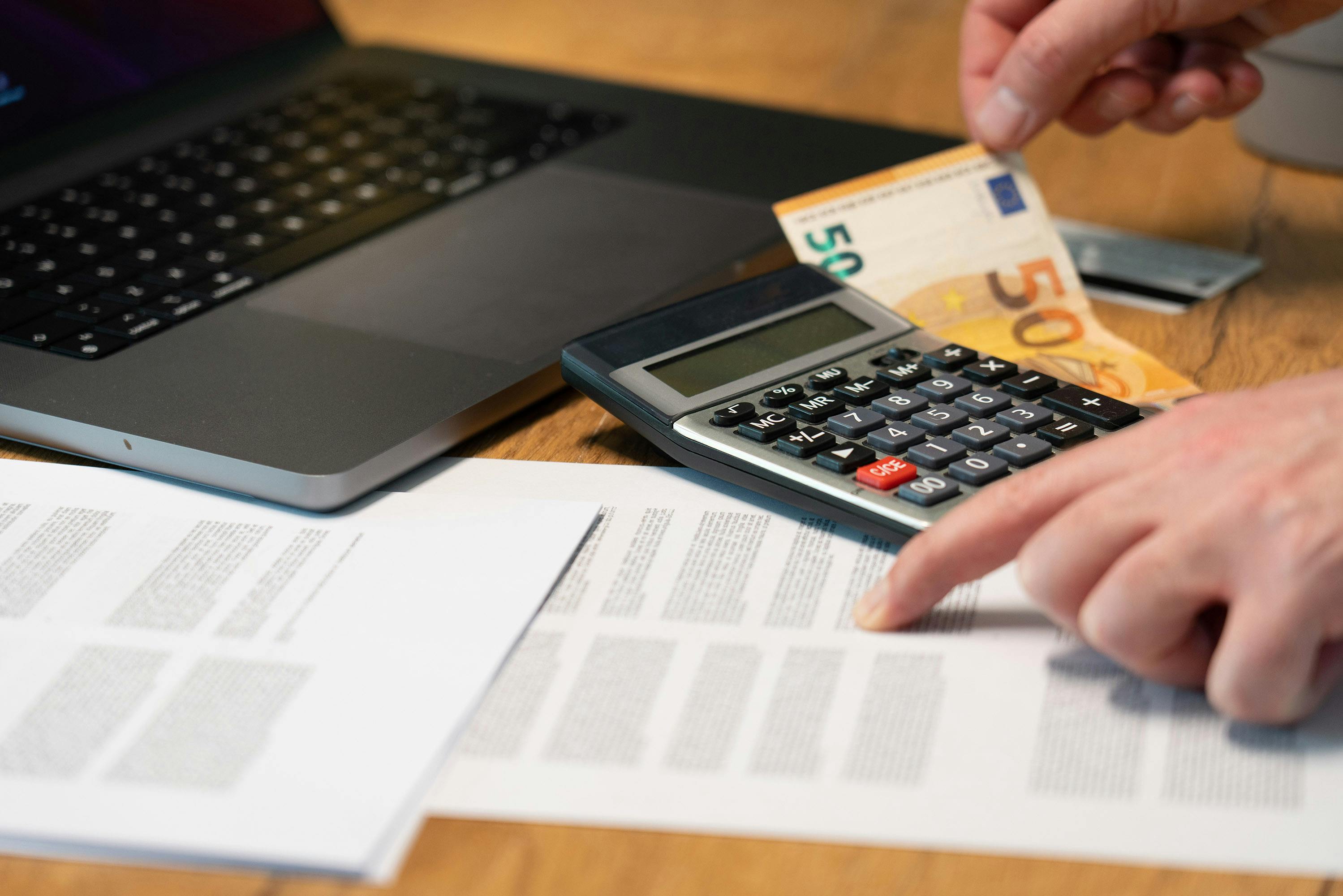Paperwork, calculator, and documents spread across a desk.